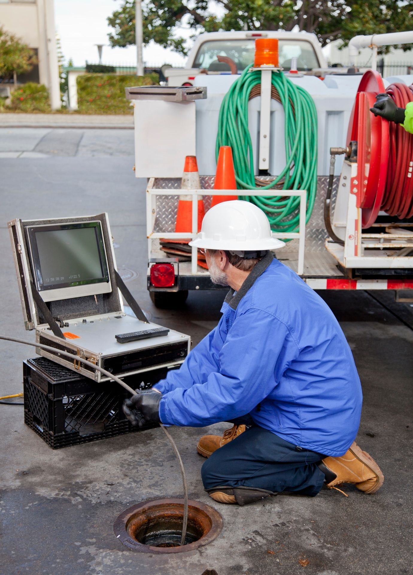 Technician using sewer camera inspection equipment at a manhole